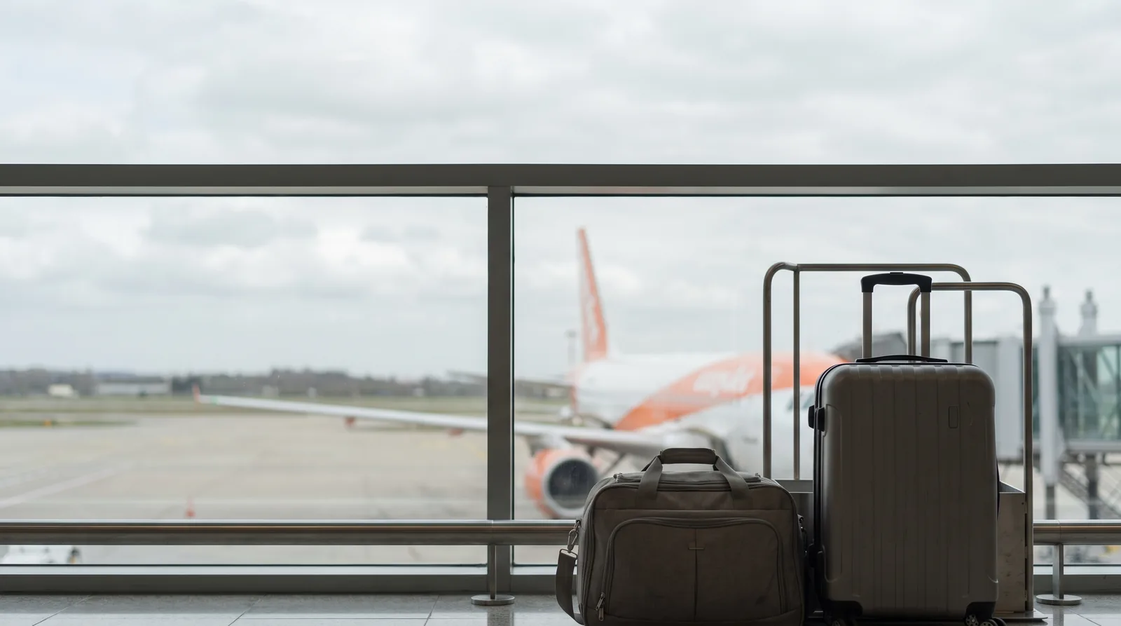 Borsa sotto il sedile e trolley grande accanto al misuratore, Airbus arancione sullo sfondo